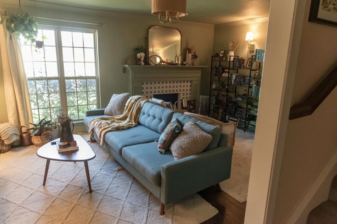 A living room with an arched mirror over the mantel