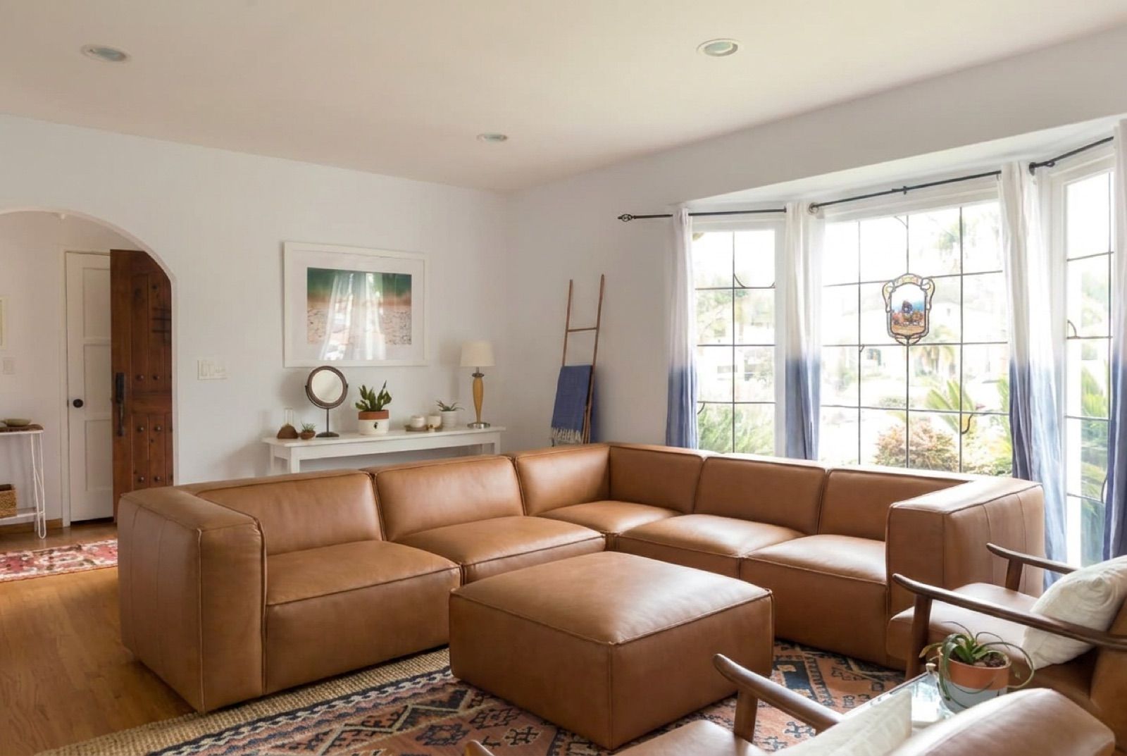 A bay window living room with a caramel leather modular sectional